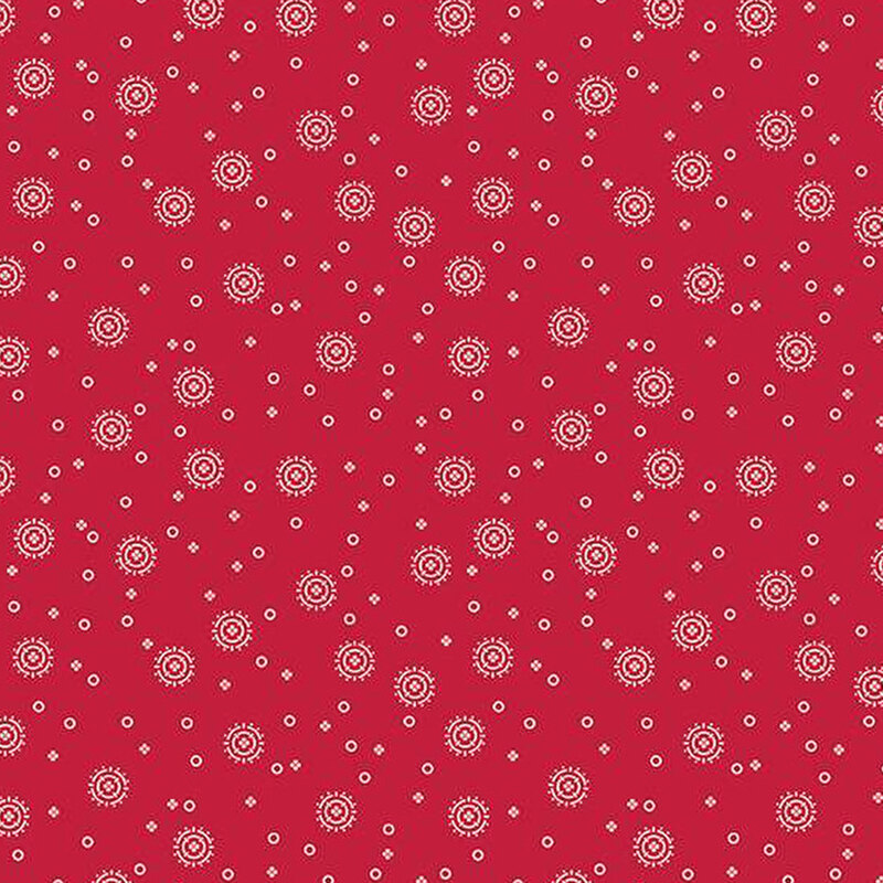 red fabric with tiny white circles and four-petaled flowers with larger circular sunbursts scattered across the fabric