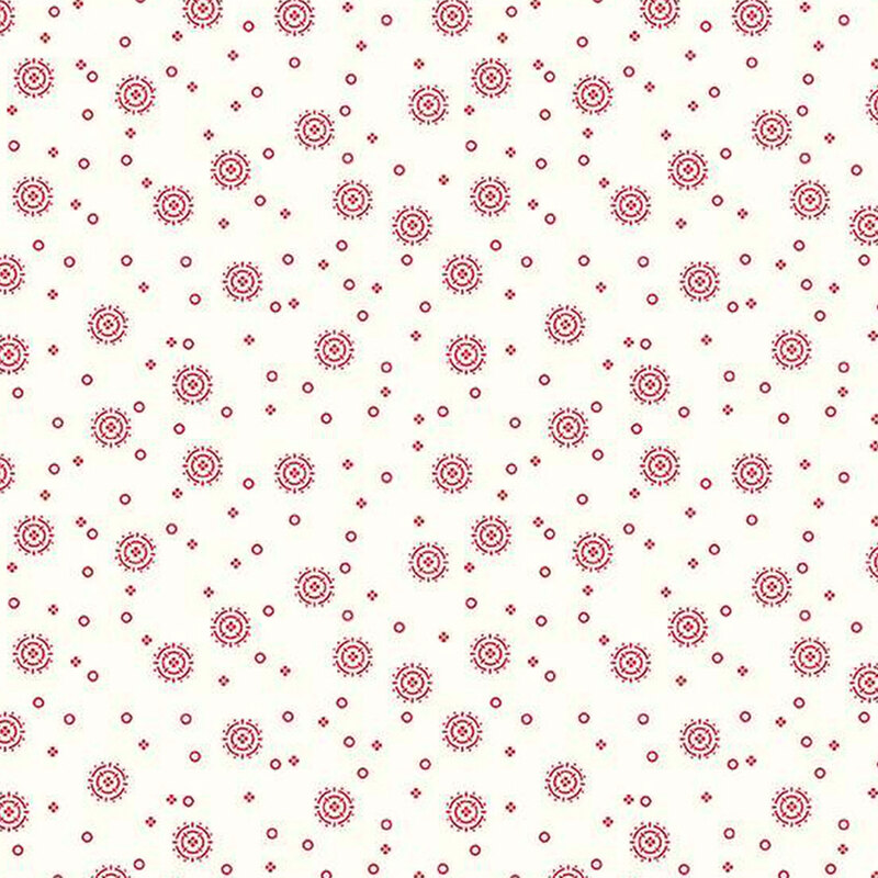 white fabric with tiny red circles and four-petaled flowers with larger circular sunbursts scattered across the fabric