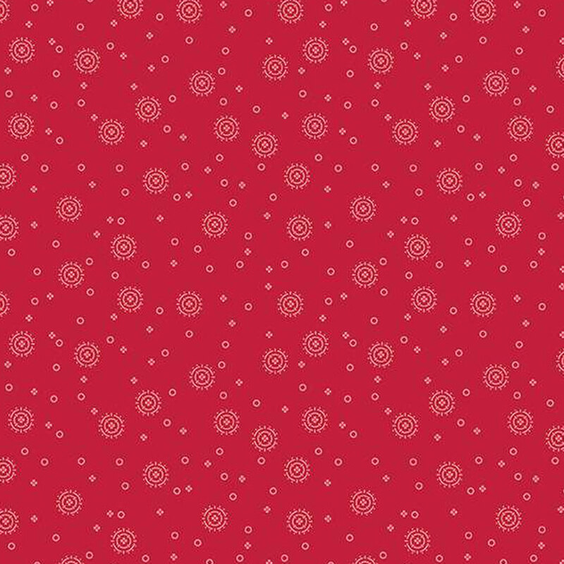 tonal red fabric with tiny circles and four-petaled flowers with larger circular sunbursts scattered across the fabric