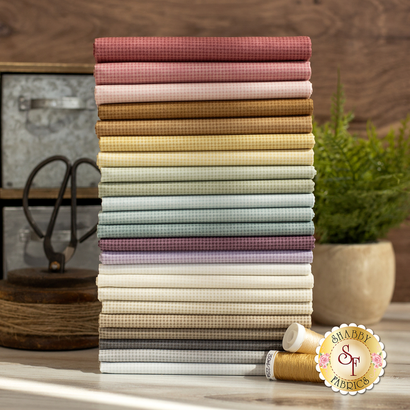 A photo of fat quarters of different color muted fabric ranging from red, to green, to purple with a subtle texture