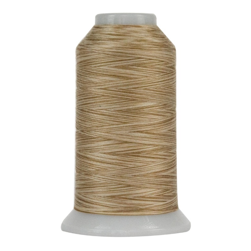 Sandy tan and creme spool of variegated thread, isolated on a white background.