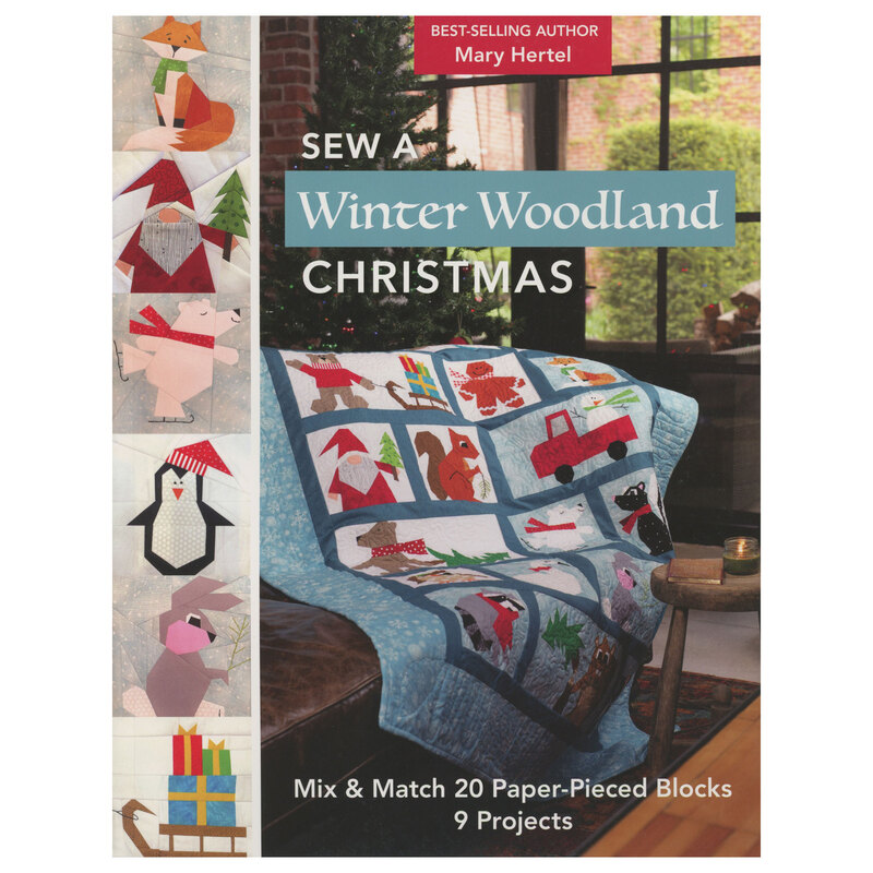front of Sew A Winter Woodland Christmas pattern book, featuring closeups of quilt blocks on the left side next to a finished version of the full quilt displayed on a couch in front of a Christmas tree
