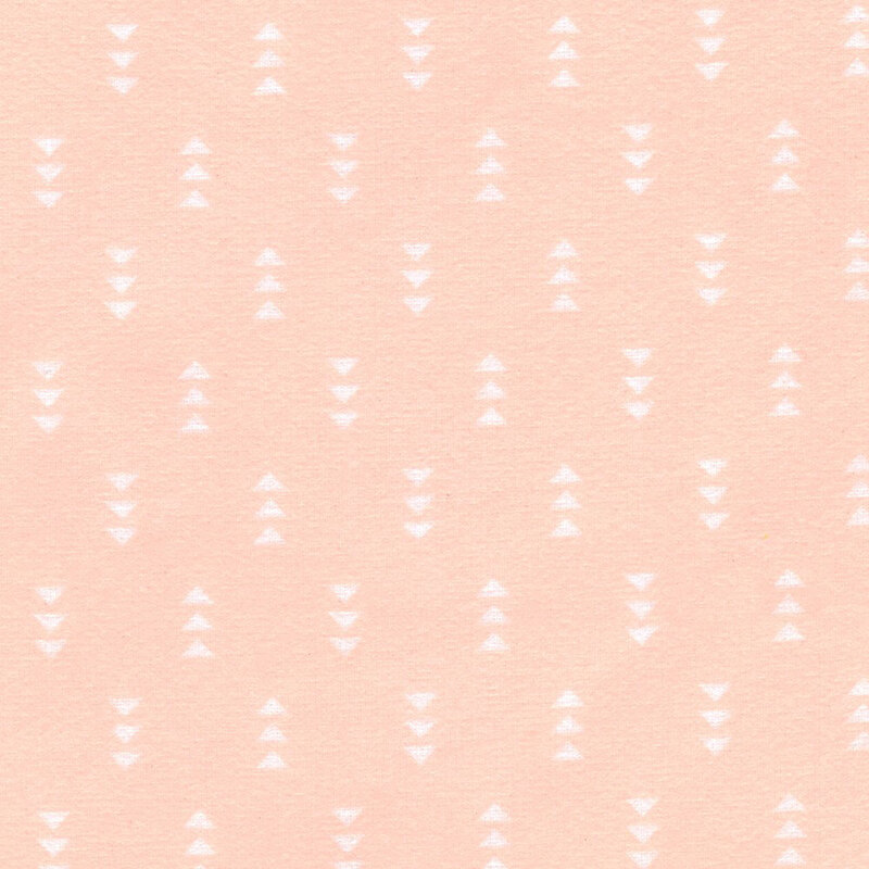 Pastel peach fabric featuring a pattern of white triangles
