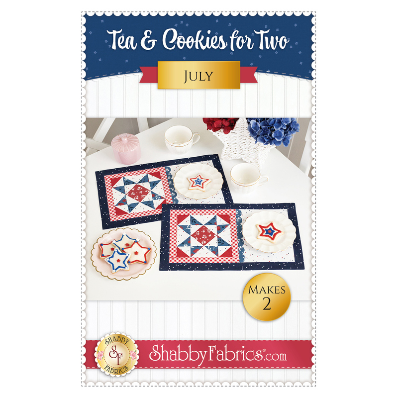 Front cover of pattern showing the completed July placemats, stated with patriotic star shaped cookies, white tea cups, a pink sugar caddy, and red and blue flowers.