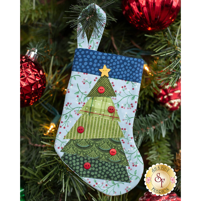 The completed Christmas Tree stocking, hung on a green Christmas tree decorated with red bulbs.