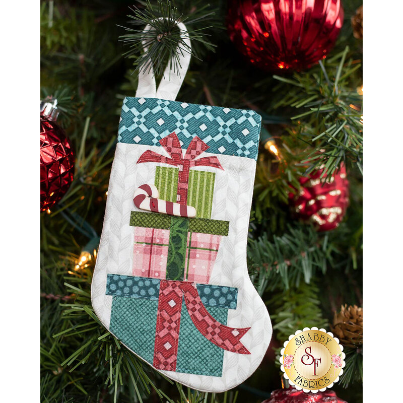 The completed Gifts stocking, hung on a green Christmas tree decorated with red bulbs.