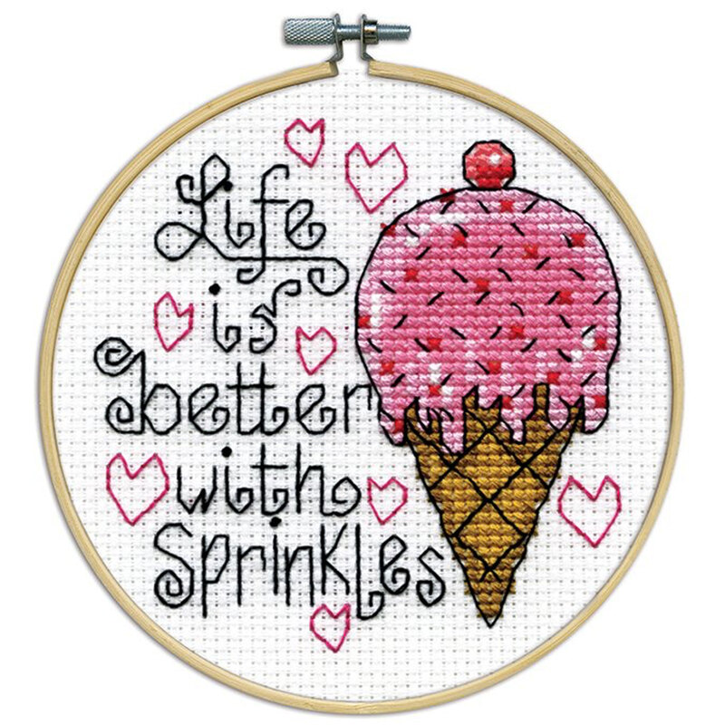 A closeup of the finished Sprinkles cross stitch inside a wooden hoop isolated on a white background.
