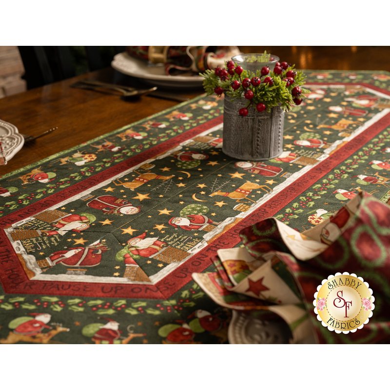 A side shot of the table runner with a holly display in the middle with three plates set with silverware and coordinating Up On The Housetop napkins on either side of the runner.