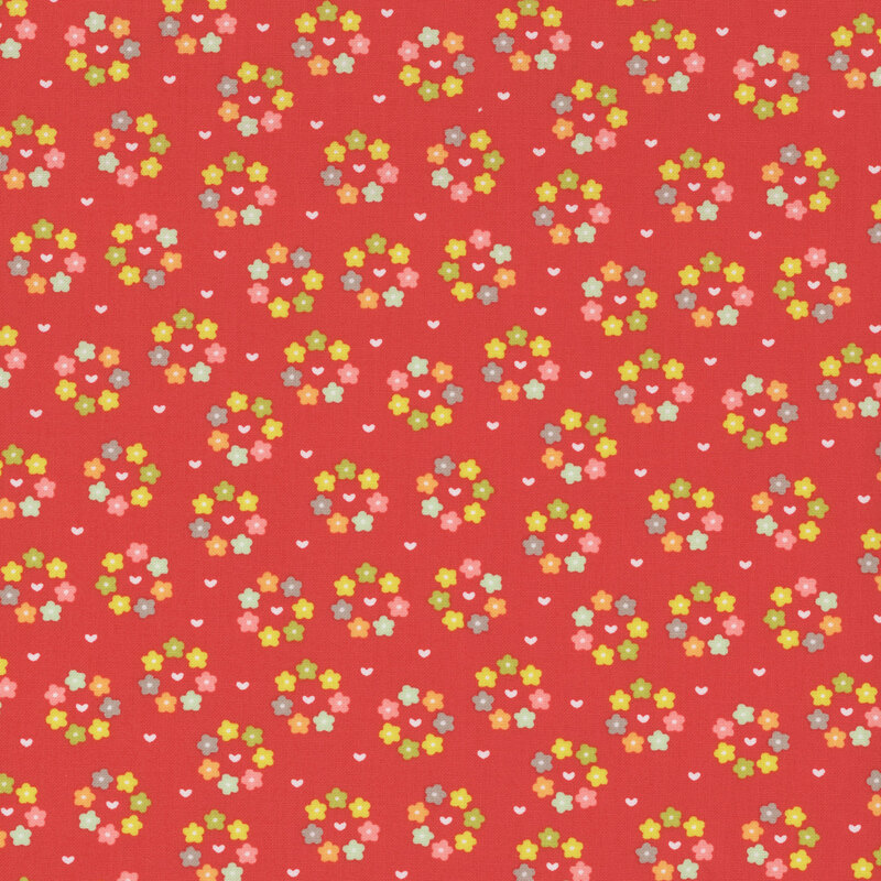 Tangerine red fabric with small white hearts surrounded by rings of multicolored flowers.