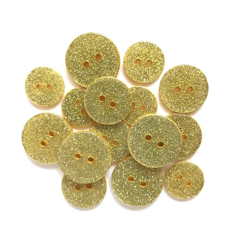 Pile of yellow glitter buttons against a white background