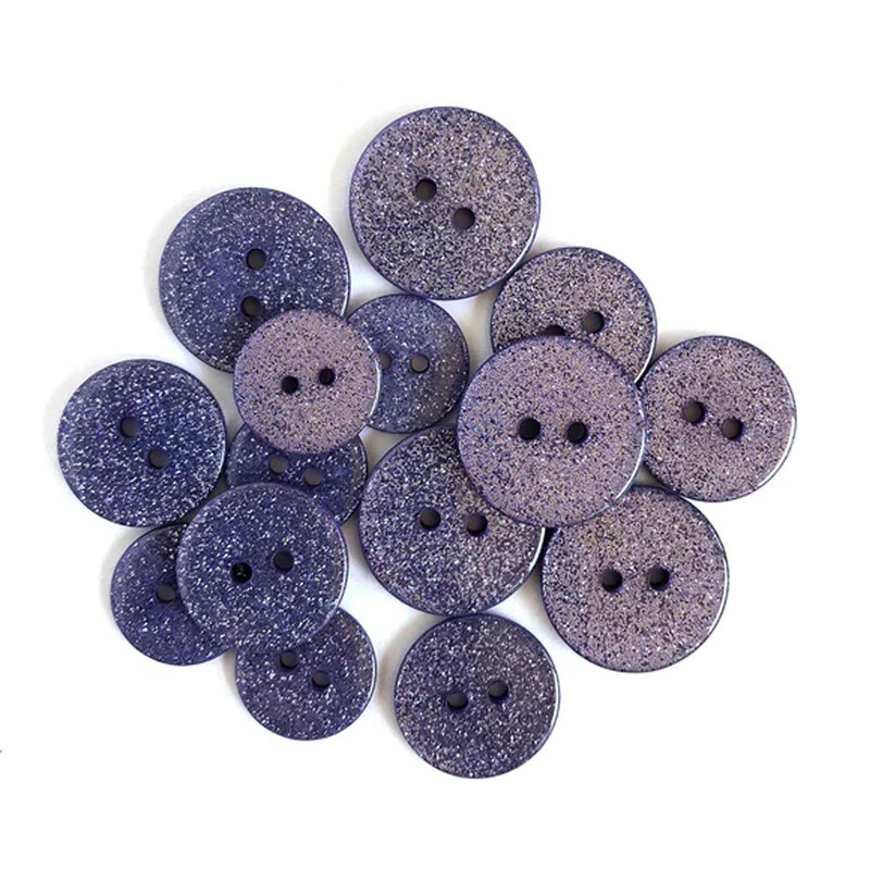 Pile of purple glitter buttons against a white background