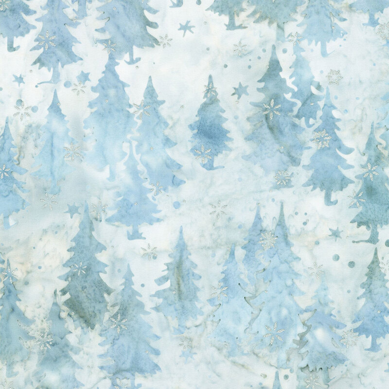 Batik fabric pattern featuring various shades of blue trees and metallic snowflakes on a light background.