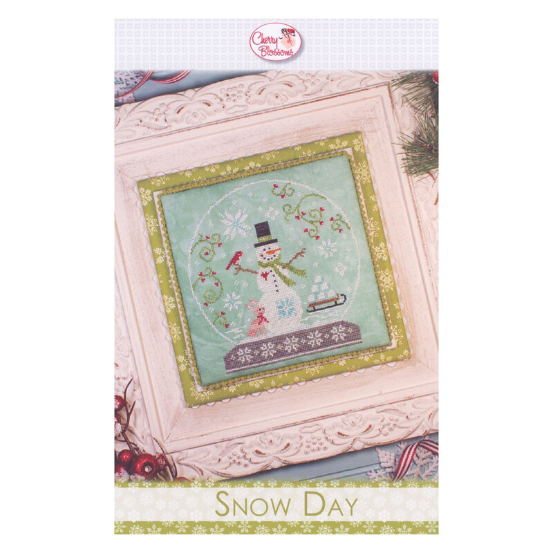 A decorative framed cross stitch project featuring a colorful snowman in a snowglobe, amid snowflakes and holiday decorations.