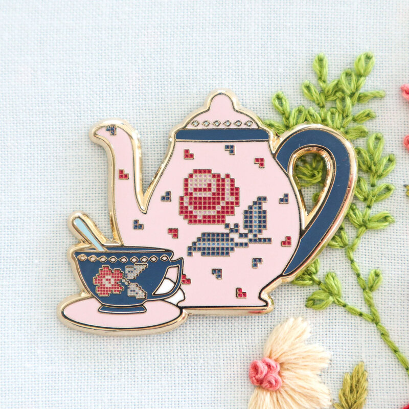 The rose tea set needle miner displayed on a hand embroidery project.