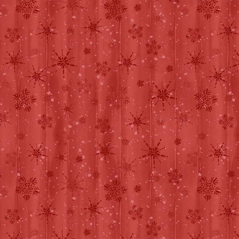 Tonal red fabric with a red background and scattered snowflakes and a wood grain textured background.