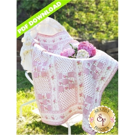 9-patch pink and white baby quilt with pink rose florals resting in bassinet.