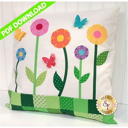 White polka-dotted pillow with colorful flower and butterfly applique shapes.