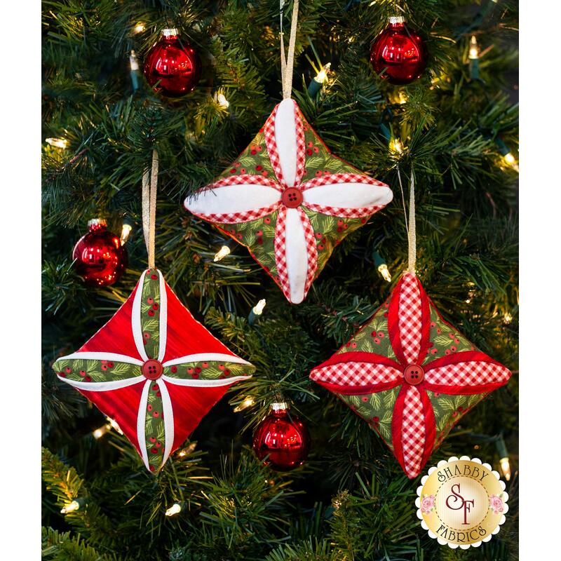 Three red and green quilted ornaments in the Cathedral Window style with red central buttons.