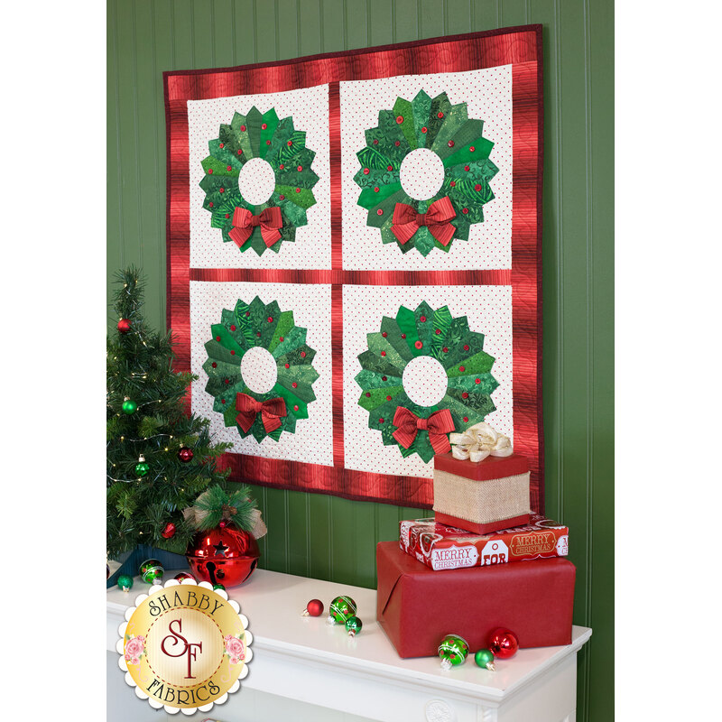 Four green Dresden plate wreaths with red 3-D bows on a cream windowpane backing with red frame.
