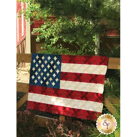 Cathedral Window style American flag quilt hanging on a wooden fence.