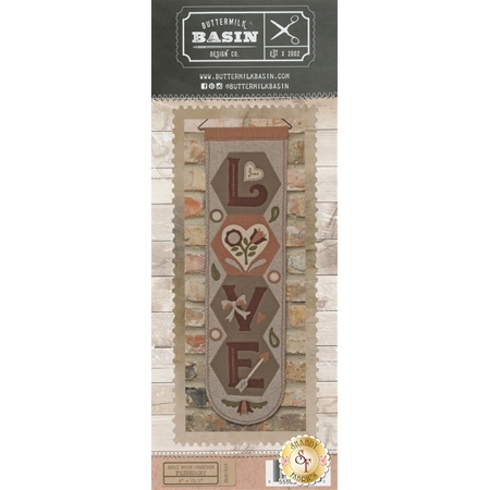 Hexi Door Greeter February Pattern front cover showing the finished project with the word LOVE sounded by hearts, flowers, bows and an arrow.