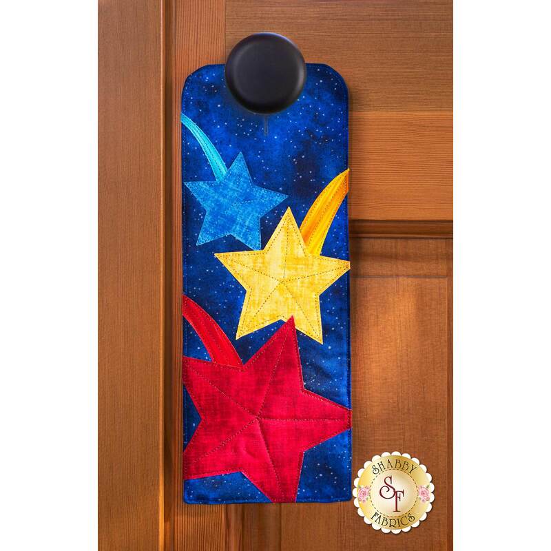 Door hanger kit for A-door-naments July with blue, yellow, & red shooting stars on deep blue fabric.