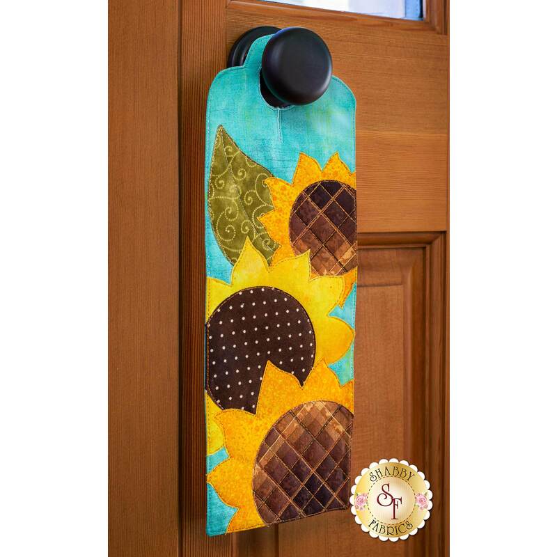 Door hanger kit for A-door-naments August with three yellow sunflowers on teal fabric.
