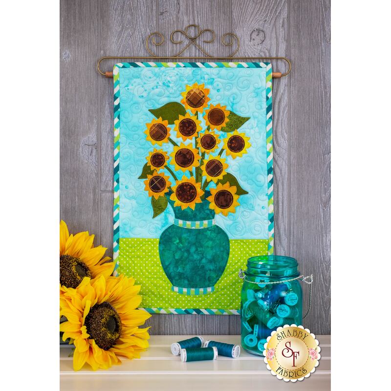 Collection of sunflowers in teal vase.