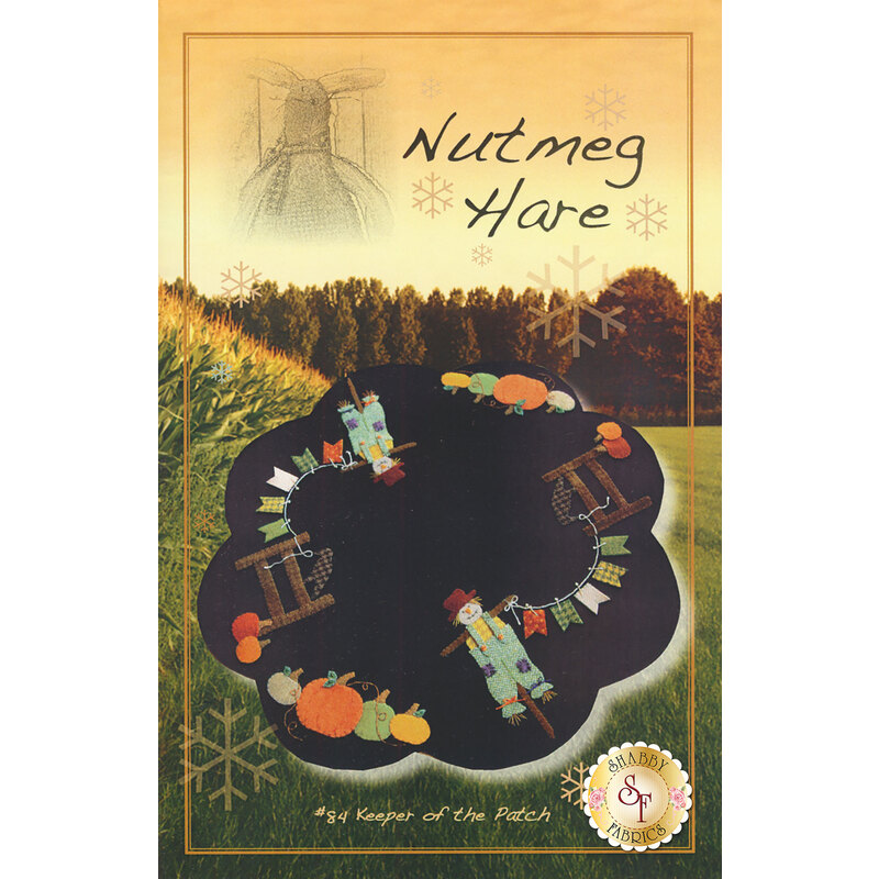 The front cover of the Keeper of the Patch Pattern showing the finished mat with a scarecrow holding a banner connected to a fence with pumpkins on the ground nearby.