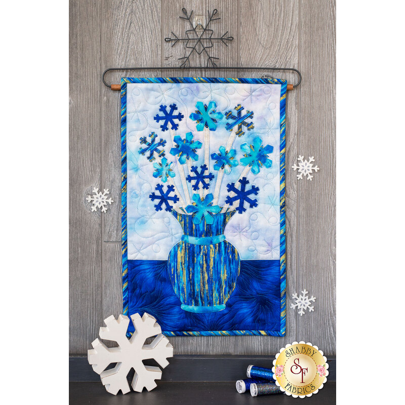 Blue snowflakes on white stems in a blue streaked vase.