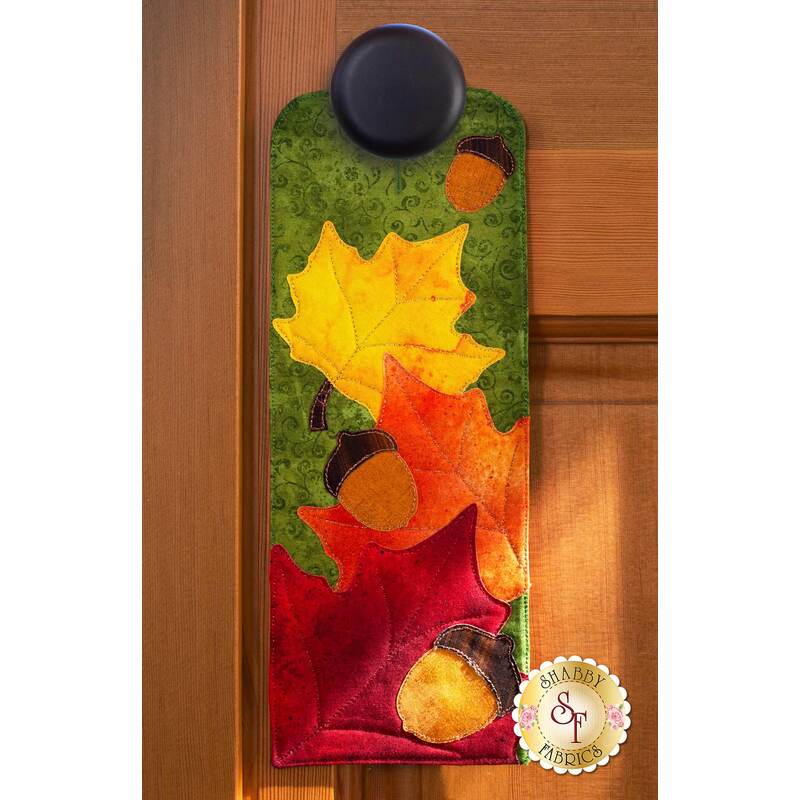 Door hanger kit for A-door-naments November with autumn leaves and acorns on green fabric.