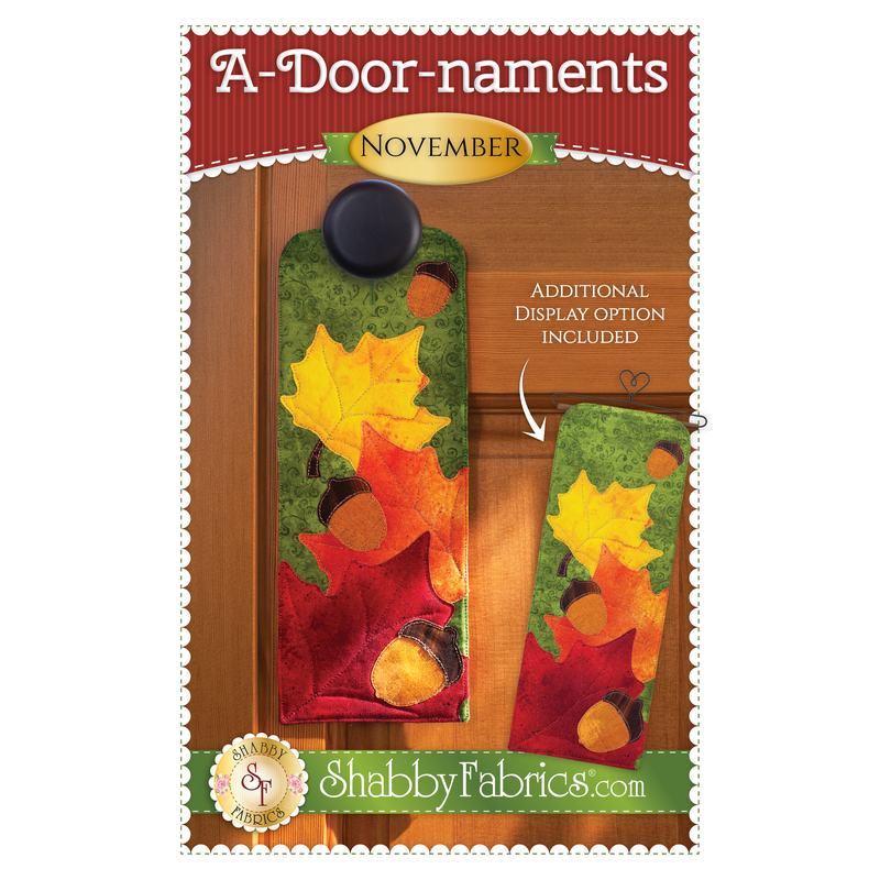 Pattern cover for A-door-naments November with autumn leaves and acorns on green fabric.