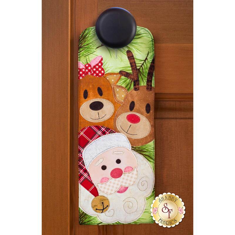 Door hanger kit for A-door-naments December with two reindeer and Santa on green fabric.