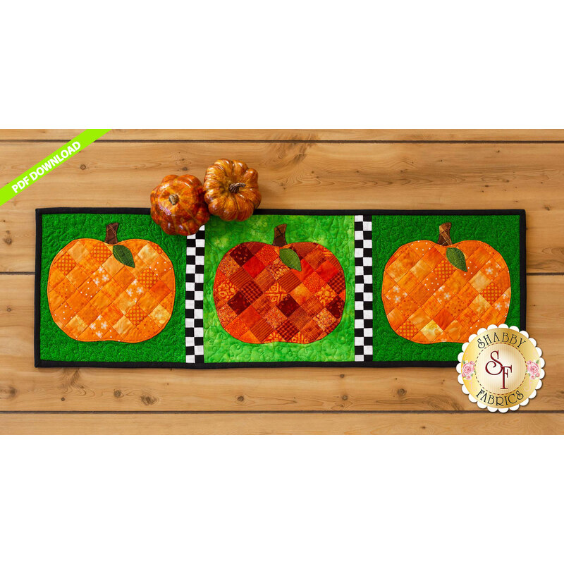 Table runner featuring orange patchwork pumpkins on green print backgrounds.
