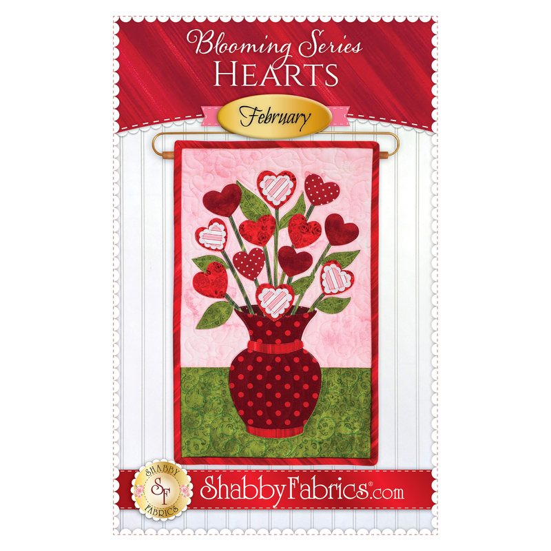 The front of the Blooming Series - February pattern by Shabby Fabrics showing the finished wall hanging with a bouquet of hearts.