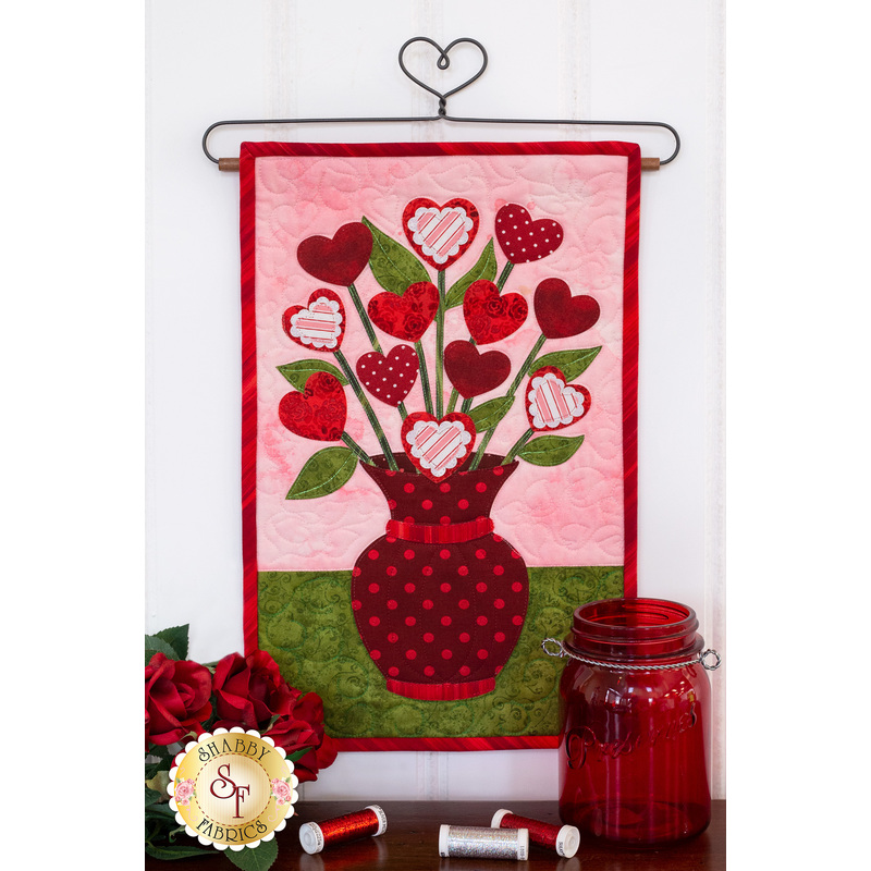 Deep red polka-dotted vase filled with red and pink hearts on stems.