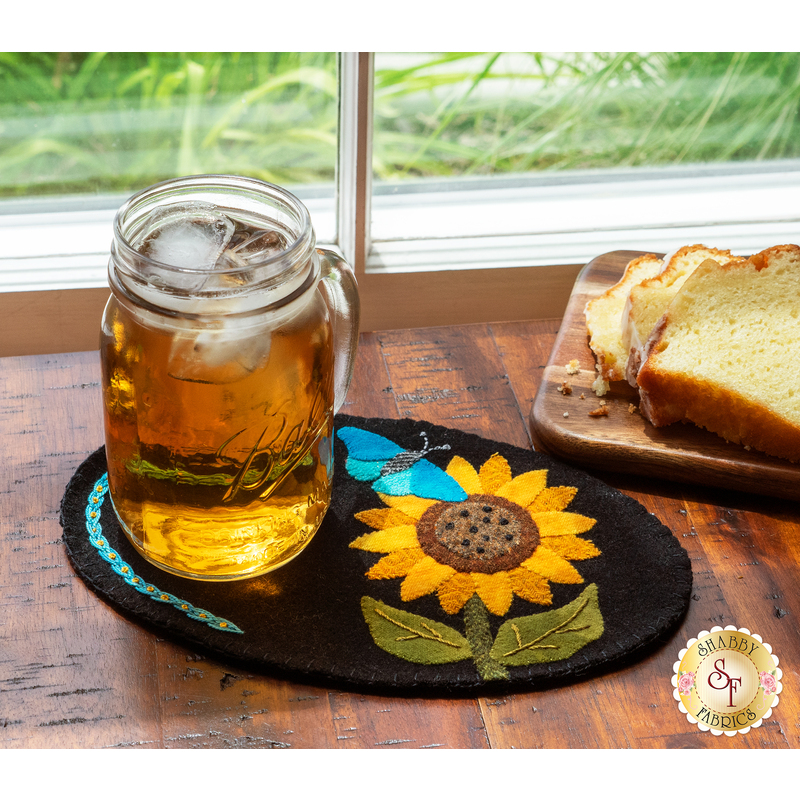 Black wool mug mat with a beautiful applique butterfly and sunflower and jar of sweet tea on top