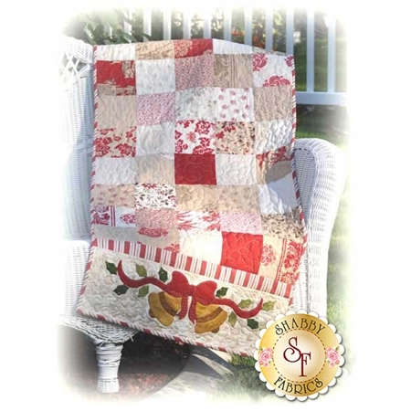Table runner with red, pink, and white square patchwork with a pair of appliqued Christmas bells.