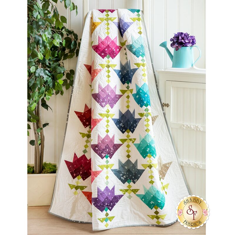 The Ombre Flower Bouquet Quilt draped next to a cabinet | Shabby Fabrics