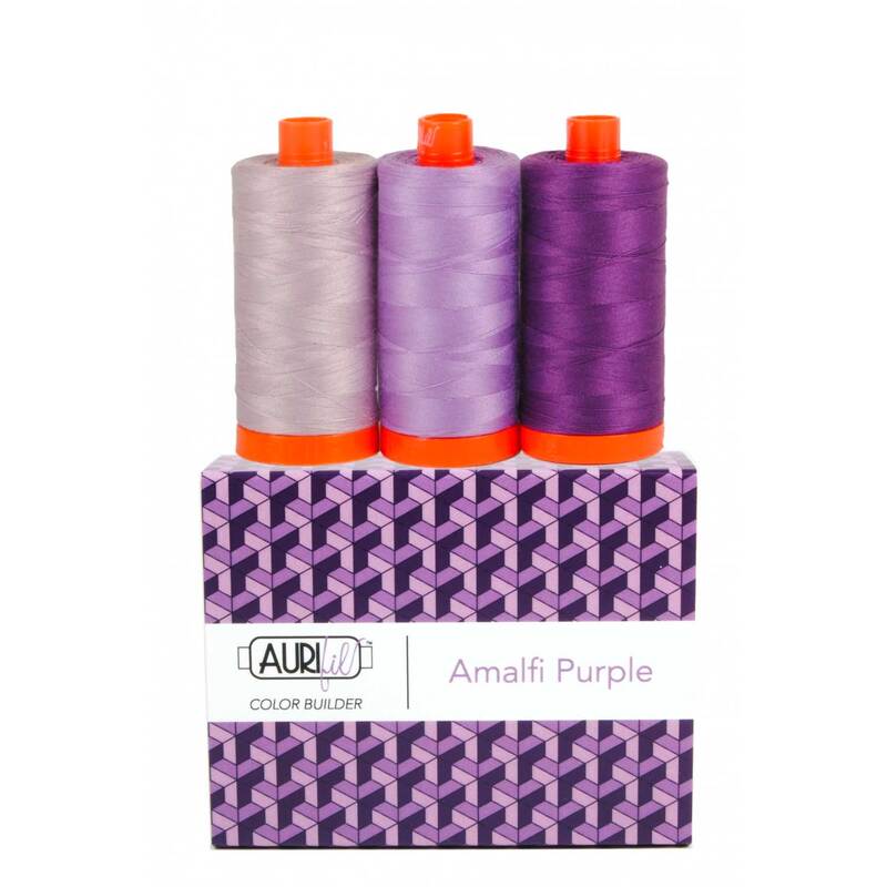 A spool of light, medium, and dark purple thread on an Aurifil Colorbuilder box