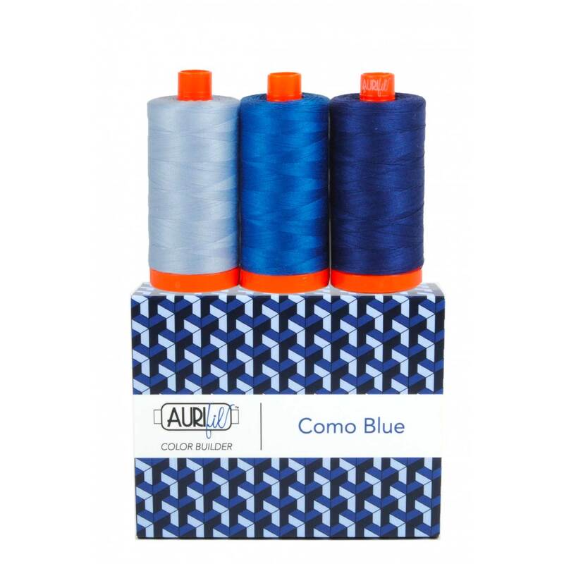 A spool of light, medium, and dark blue thread on an Aurifil Colorbuilder box