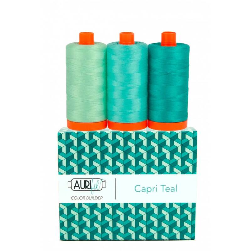 A spool of aqua, turquoise, and dark teal thread on an Aurifil Colorbuilder box