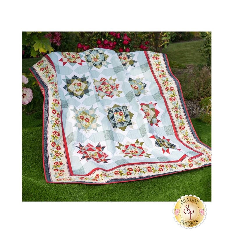 A beautiful summer quilt with Enchanted Garden fabrics displayed on a wall