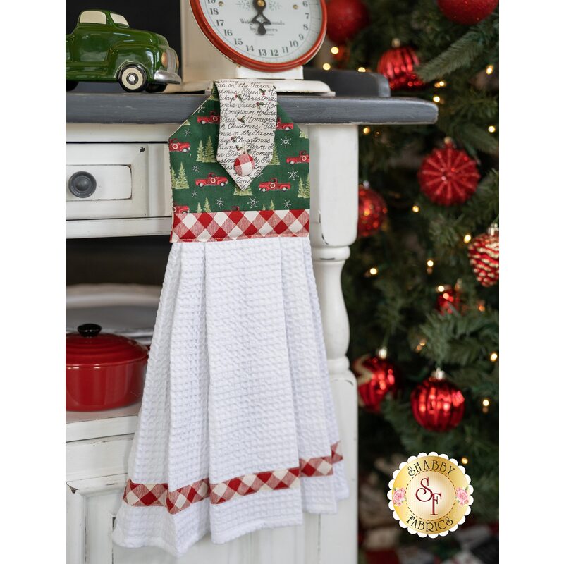 Green and white Christmas themed hanging towel displayed hanging from a cabinet