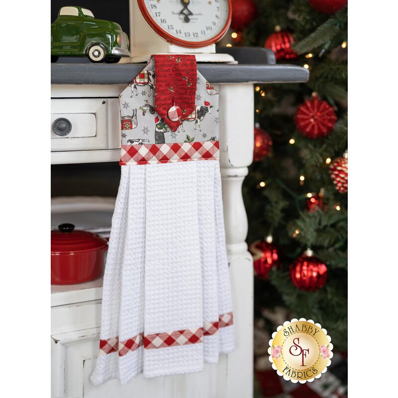 A gray and red Christmas themed hanging towel hung from a cabinet