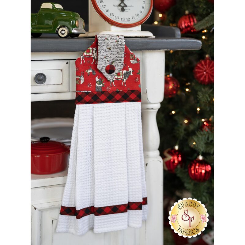 Red and gray themed hanging towel displayed hanging from a cabinet